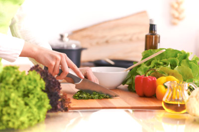 Close Up of human hands cooking vegetable salad in kitchen on the glass table with reflection